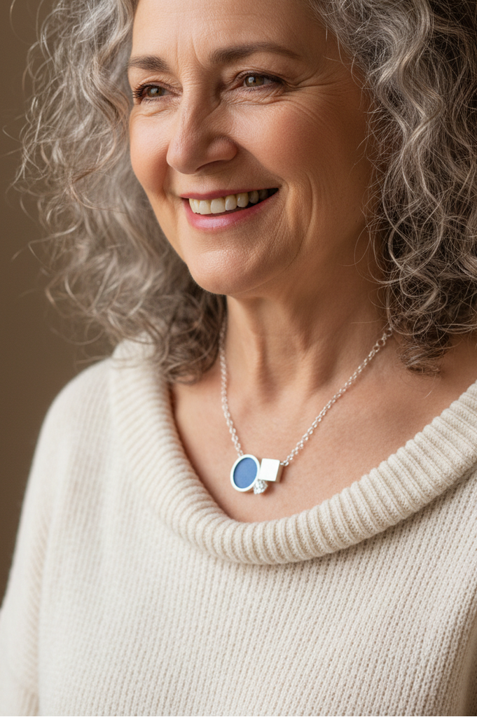 Kettenanhänger aus Silber, "menage á trois", Kreis, Quadrat und sechseckiger Bergkristall an silberner Kette, eine sympathische grauhaarig gelockte Frau trägt den Schmuck